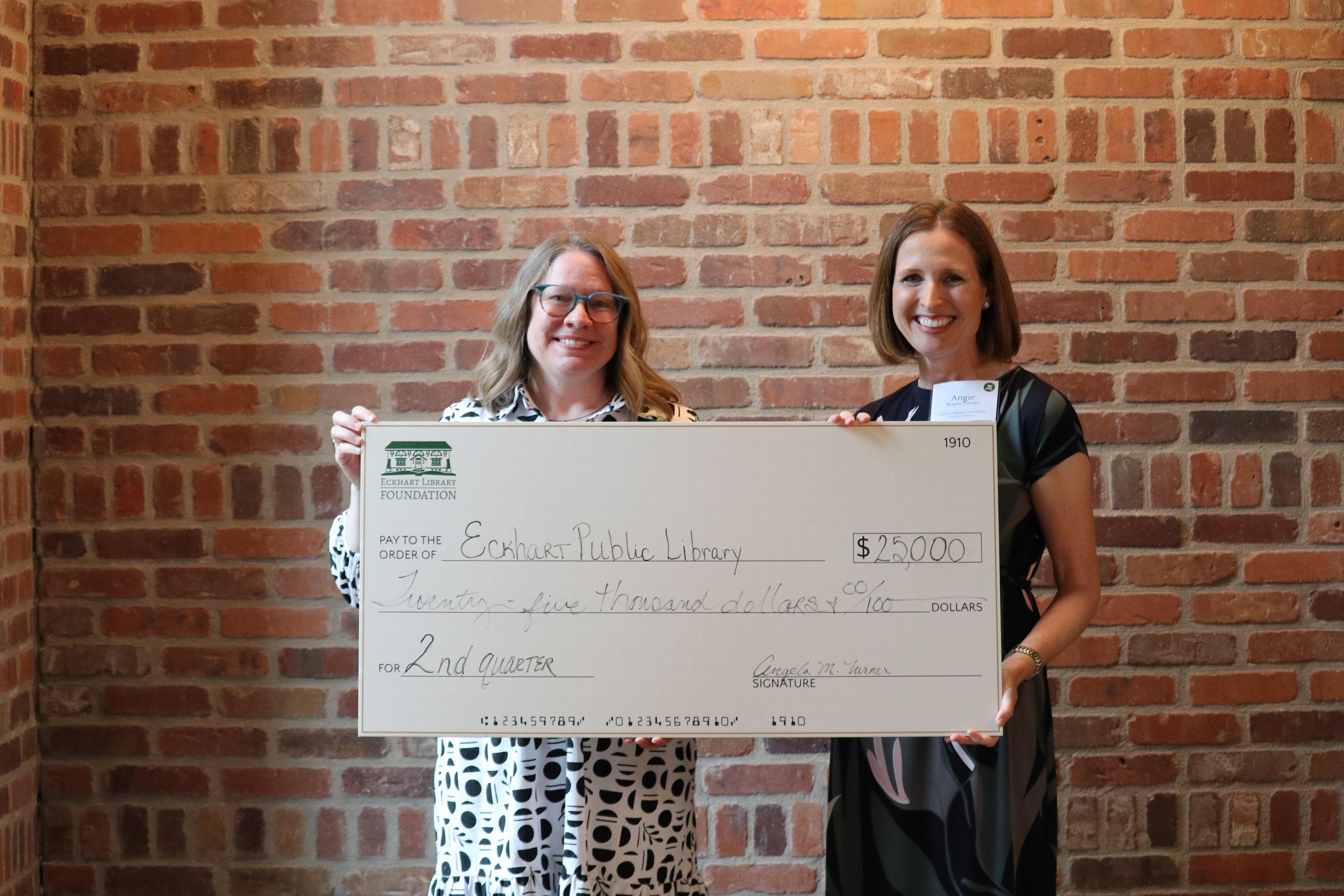 man handing check to woman infront of artwork